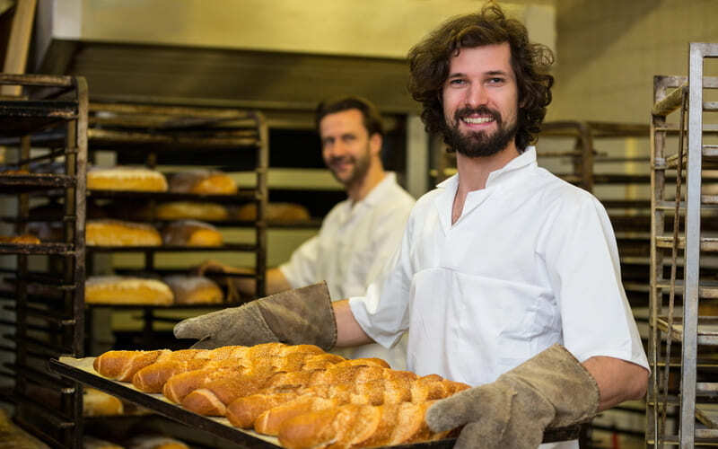 Bäcker hält ein Blech mit Backwaren